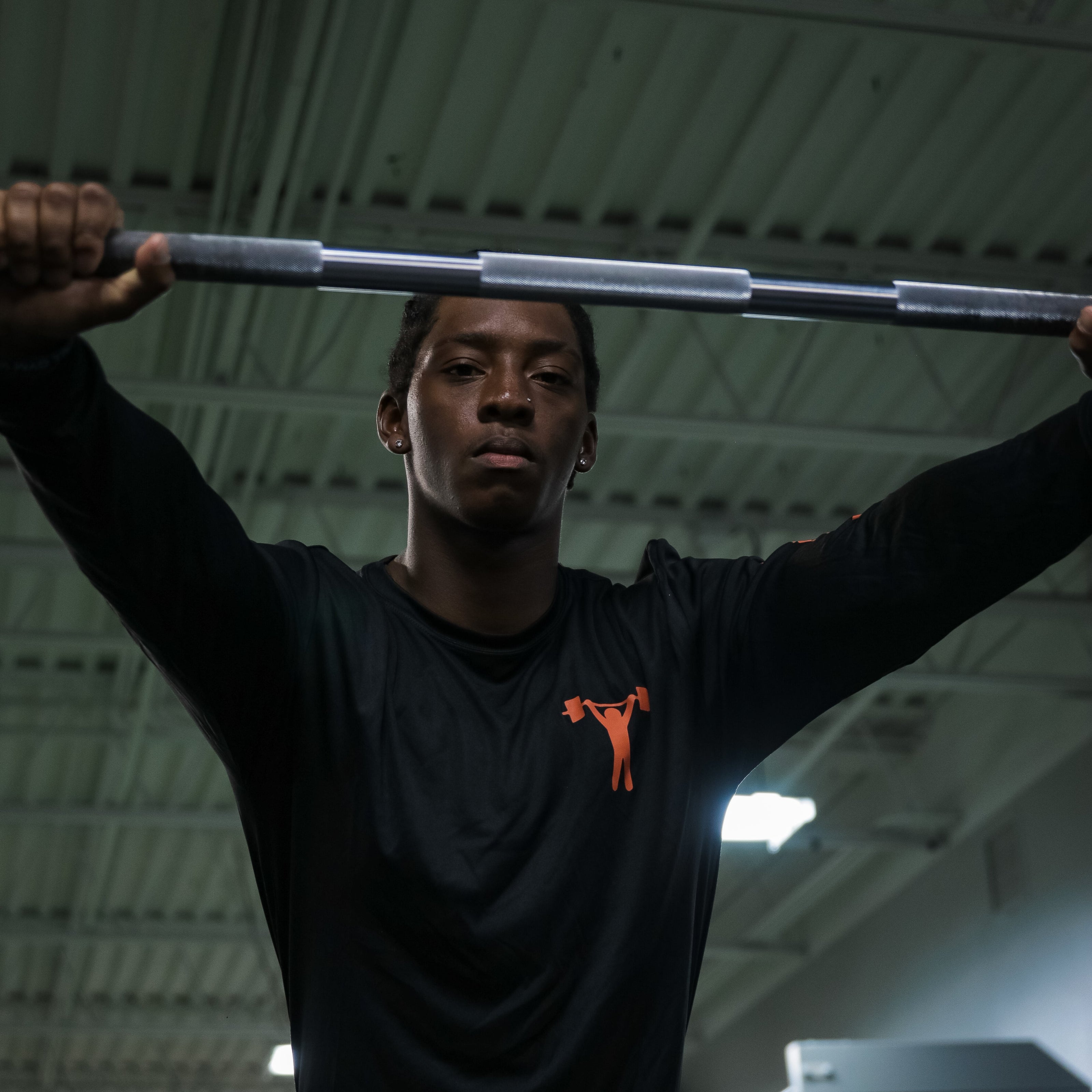 Photo of a young man resting forward on a barbell